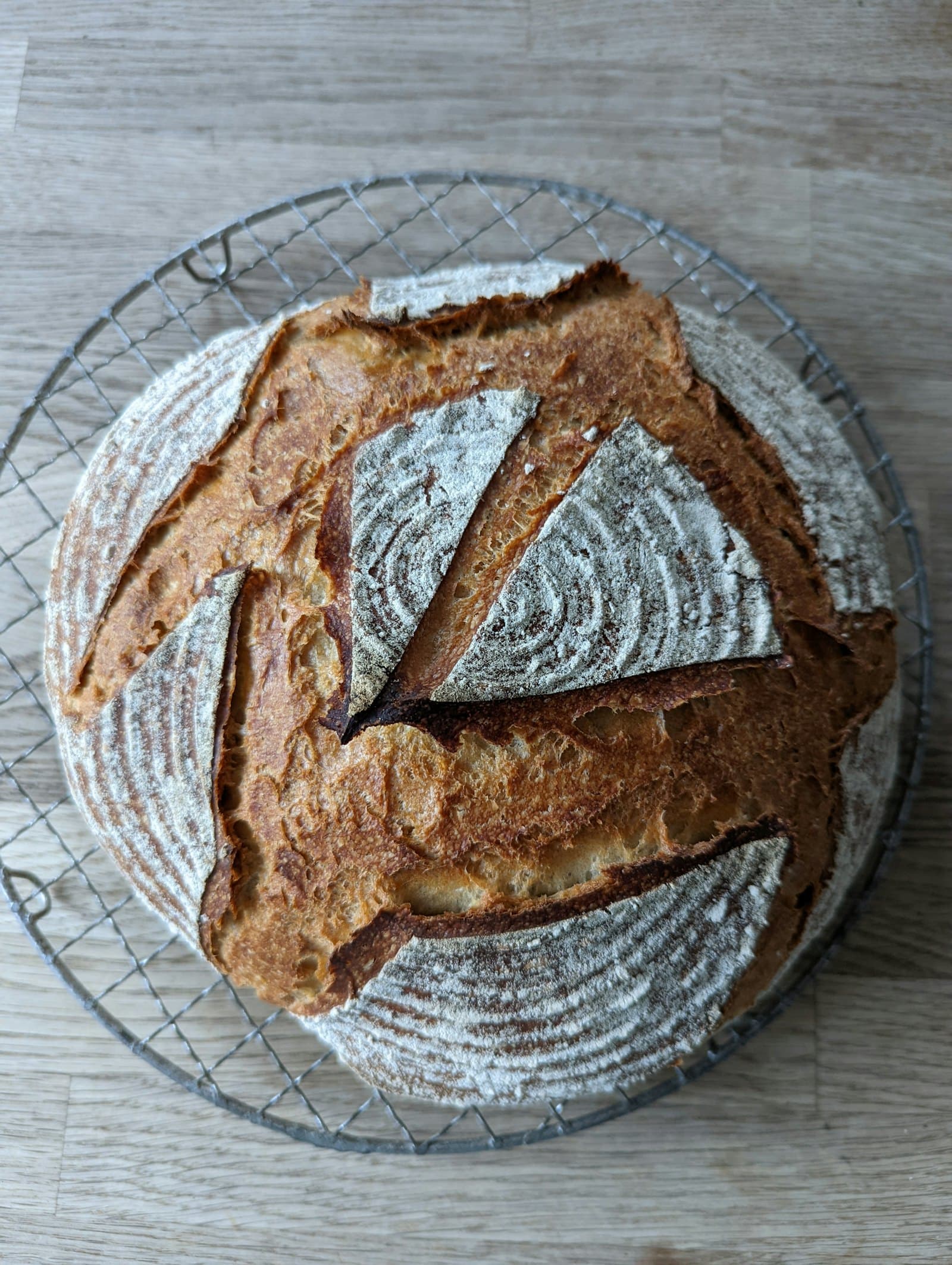 A scored sourdough loaf cooling on a wire rack