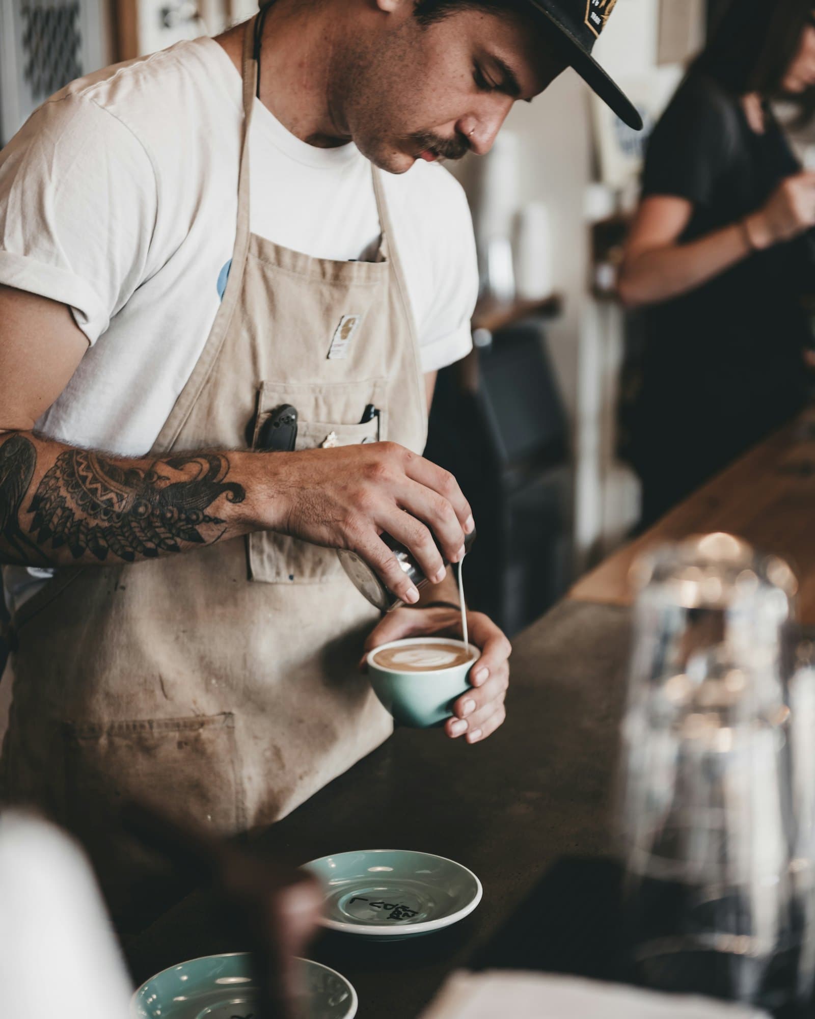 A barista pouring milk into a flat white